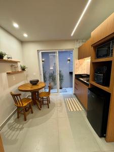 eine Küche mit einem Holztisch, Stühlen und einem Tisch in der Unterkunft Flat Pé na Areia Iriri T03 - Conforto a 3 Min da Praia in Anchieta