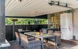 a patio with a table and chairs and a refrigerator at Three-Bedroom Holiday Home In Vaggerlose in Marielyst