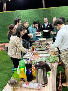 a group of people standing around a table with food at استراحة الأسطورة AlAstura rest in Al Ḩamrāʼ