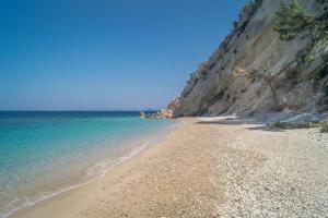 a sandy beach next to the ocean on a cliff at Armonia Bay Hotel in Kokkari