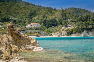 a view of a beach with a house on a mountain at Armonia Bay Hotel in Kokkari