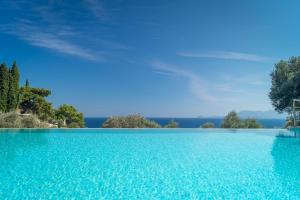 a pool of blue water with trees in the background at Armonia Bay Hotel in Kokkari