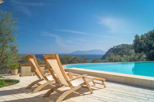 two chairs sitting next to a swimming pool at Armonia Bay Hotel in Kokkari