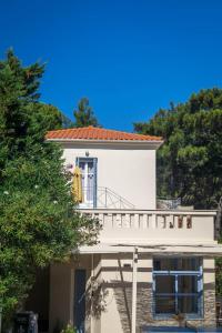 a white house with a balcony and trees at Armonia Bay Hotel in Kokkari