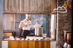 a man cooking in a kitchen with a pot at Bakhan Village Resort in Mai Châu