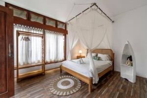 a bedroom with a bed with a mosquito net at Family Oasis, 2 Bedrooms, Shared Pool, Garden, Rice Field View in Ubud