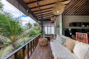 an outdoor balcony with a couch and palm trees at Family Oasis, 2 Bedrooms, Shared Pool, Garden, Rice Field View in Ubud