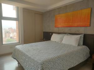 a bedroom with a bed with a checkered blanket and two windows at Apartasuites AV in Medellín +21 photos