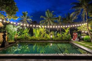 a swimming pool in a garden at night with lights at Family Villa, Shared Pool, Garden, Rice Field & Jungle Views in Ubud