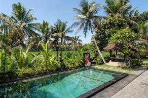 a swimming pool in front of a resort with palm trees at Family Villa, Shared Pool, Garden, Rice Field & Jungle Views in Ubud