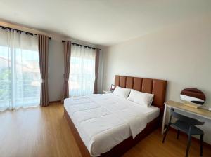 a bedroom with a bed with a desk and a window at Monday Guesthouse Hatyai in Hat Yai