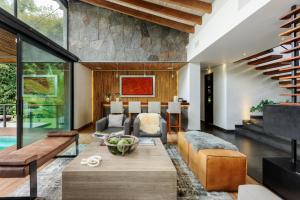 una sala de estar de planta abierta con una pared de piedra. en Casa Galo-Modern Retreat Overlooking Golf Course, en Valle de Bravo