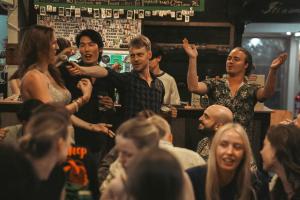 Eine Gruppe von Leuten in einer Bar mit erhobenen Händen. in der Unterkunft Stamps Backpackers in Chiang Mai