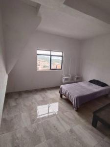 ein weißes Zimmer mit einem Bett und einem Fenster in der Unterkunft Departamento linda vista in Guanajuato