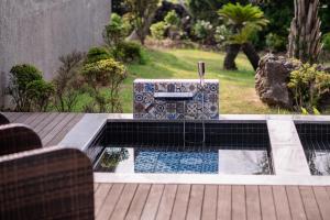 a swimming pool with a fountain in a garden at Ceylon Jeju Pool Villa in Jeju