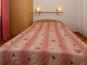 a bed with a pink bedspread with butterflies on it at Beachfront Apartments Andrijević in Brist
