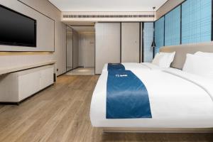 una camera da letto con un letto grande e una TV a schermo piatto di Echarm Hotel Changsha Provincial Government Desiqin Branch a Changsha