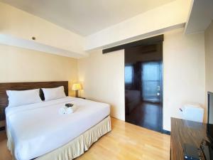a bedroom with a large white bed and a door at Cozy 1BR Apartment at Braga City Walk By Travelio in Bandung