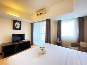 a hotel room with a bed and a television at Cozy 1BR Apartment at Braga City Walk By Travelio in Bandung