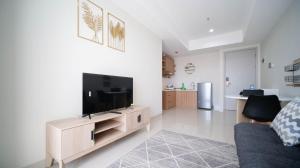 a living room with a flat screen tv on a entertainment center at Minimalist with Beautiful View 2BR at Grand Sungkono Lagoon Apartment By Travelio in Surabaya