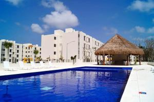 a hotel with a large swimming pool and a thatch hut at Loft Joe con WiFi y Alberca in Tulum