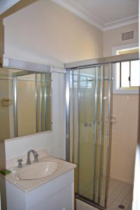 Un baño con lavabo y ducha de cristal. en Clarkes Flat 4, en South West Rocks