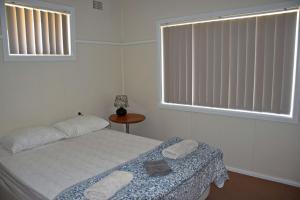 1 dormitorio con 1 cama, 2 ventanas y mesa en Clarkes Flat 4, en South West Rocks
