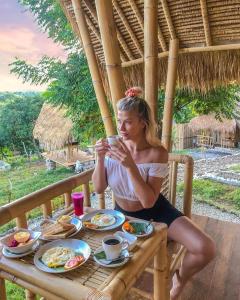 a woman sitting at a table with a plate of food at Penida Bambu Green Villas in Nusa Penida +61 photos