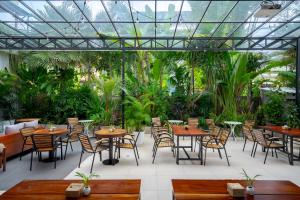 a restaurant with tables and chairs and plants at Onederz Siem Reap in Siem Reap