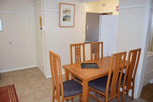 Un comedor con mesa y sillas de madera. en Clarkes Flat 4, en South West Rocks