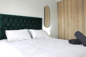 a bedroom with a white bed with a green headboard at The Jade Escape in Cape Town +7 photos