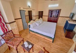 ein Schlafzimmer mit einem Bett, einem Stuhl und einem Tisch in der Unterkunft Taj Mahal Vintage Villa by VOYE HOMES in Kodaikanal