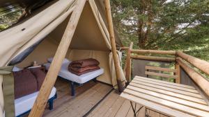 a tent with a bed and a bench on a deck at Camping le Martinet in Briare