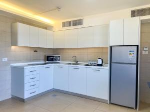 a kitchen with white cabinets and a refrigerator at Triple A Hotel Suites in Amman