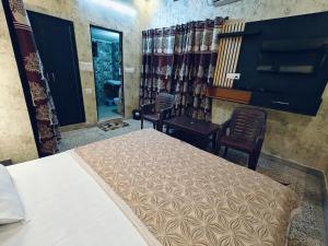 a bedroom with a bed and two chairs and a mirror at Shreeji Inn Homestay in Rishīkesh
