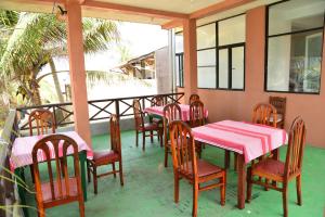 un patio con mesas y sillas rosas en un porche en Athula Hikka beach Guesthouse, en Hikkaduwa