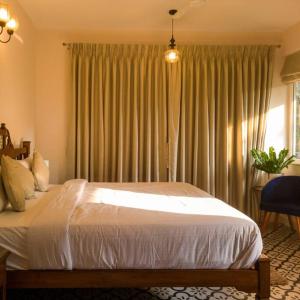 ein Schlafzimmer mit einem Bett und einem Fenster mit Vorhängen in der Unterkunft Modern villa with Private Pool,WiFi,parking in Varca in Goa + 47 Fotos