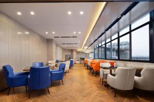 YisuheにあるEcharm Hotel Xiangtan Yichuanhe Branchの椅子とテーブルと窓のあるレストラン