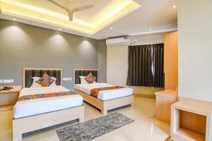a bedroom with two beds and a television at FabHotel JP - Nr Sataragachhi Railway Station in Hāora