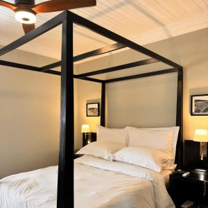 a bedroom with a black canopy bed with white pillows at Bredasdorp Square in Bredasdorp