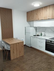 a kitchen with white cabinets and a wooden table at Apartment with pool in Veliko Gradište