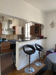 a kitchen with two bar stools in front of a counter at Appartement porte de paris in Bourg-la-Reine +10 photos