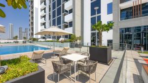 Escape24 Stylish Studio Azizi Riviera 8 Meydan one Dubai في دبي: فناء مع طاولة وكراسي بجوار حمام السباحة