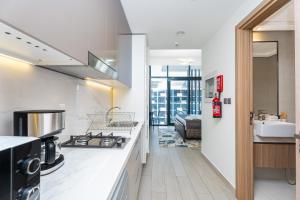 Escape24 Stylish Studio Azizi Riviera 8 Meydan one Dubai في دبي: مطبخ به كونترات بيضاء وفرن علوي
