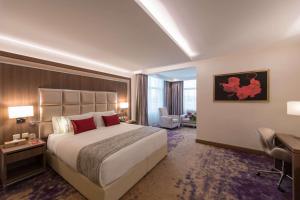 a hotel room with a large bed and a desk at Ramada by Wyndham Continental Jeddah in Jeddah