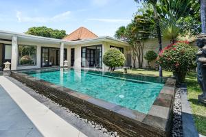 a swimming pool in front of a house at Sombra Villa by Kozystay - Sanur in Sanur