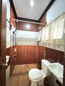 a bathroom with a toilet and a sink and a shower at Aquaholik Traveler's Lodge in El Nido