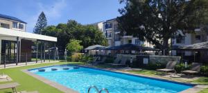 a pool with chairs and umbrellas next to a building at The Jade Escape in Cape Town