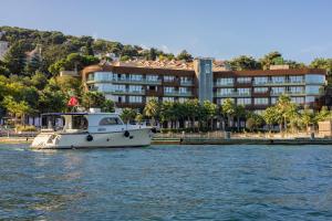 a boat in the water in front of a building at Princes' Palace Resort, Buyukada - Member of The Leading Hotels of the World in Adalar