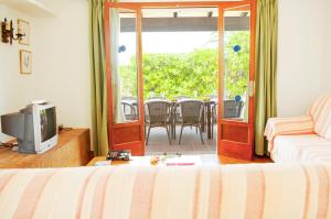 a room with a bed and a television and a balcony at Villa Solana in Portopetro